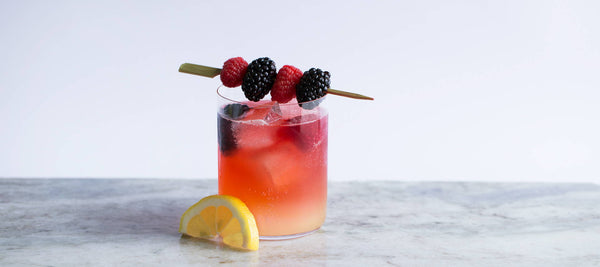 tequila sunrise cocktail with fresh berries and lemon